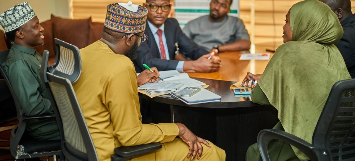 A team in discussion around a boardroom table at a northern Nigerian office