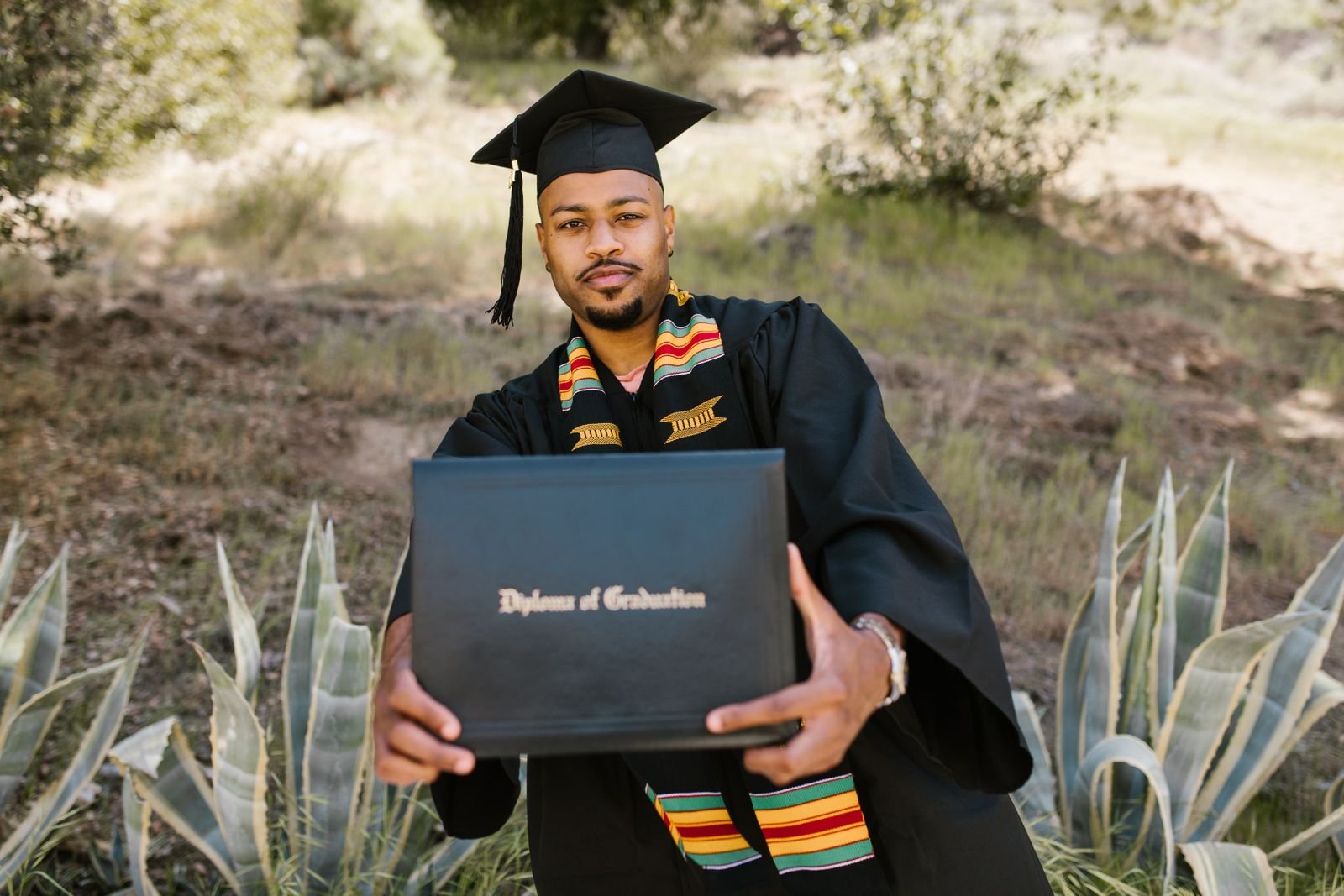 Graduates in gowns holding rolled diplomas
